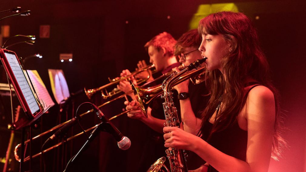 10 Mitarbeiter:innen vom Team vom Freiraum St. Pölten auf der Bühne vor rotem Vorhang. Foto: Klaus Engelmayer