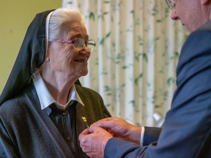 Der Bügermeister steckt die Nadel mit dem Ehrenzeichen an die Weste von Sr. Dornhackl an.