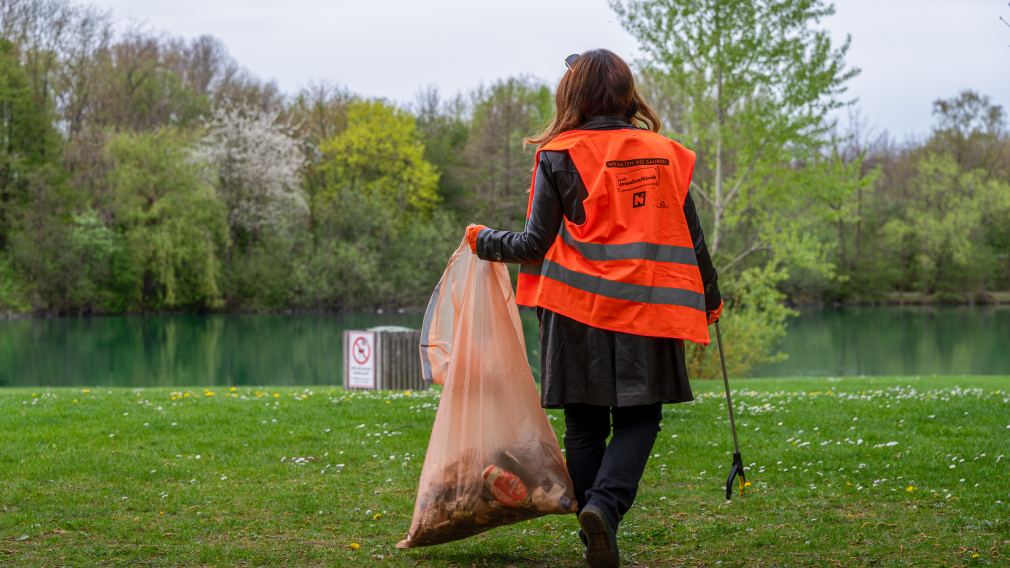 Frau am Ufer des Ratzersdorfer Sees beim Müllsammeln. (Foto: Christian Krückel)