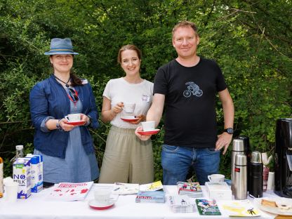Drei Mitarbeiter:innen des Magistrats stehen hinter einem Tisch mit Infomaterial im Grünen, sie halten Kaffeetassen in der Hand. (Foto: Peter Rauchecker)