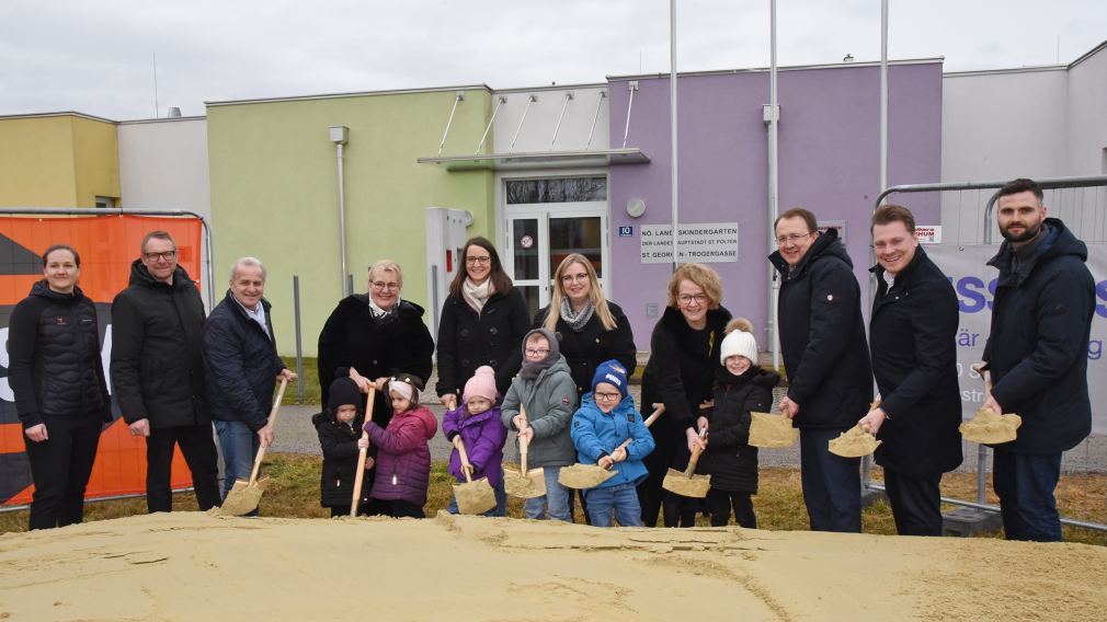 Bürgermeister Matthias Stadler, Baumeister Markus Steinwendtner, Kindergartenleiterin Marion Gnigler und Schulamtsleiter Andreas Schmidt sitzen im neuen Kindergarten mit zwei Kindern. (Foto: Vorlafuer)