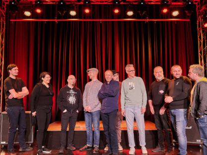 10 Mitarbeiter:innen vom Team vom Freiraum St. Pölten auf der Bühne vor rotem Vorhang. Foto: Klaus Engelmayer